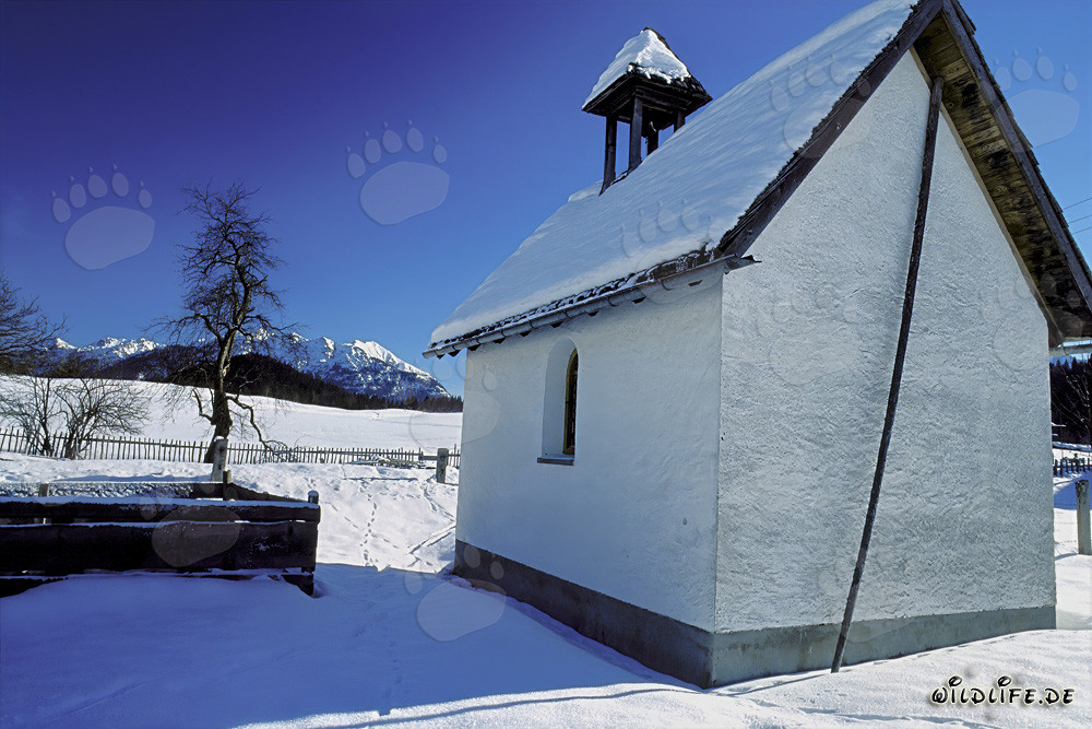 Paisaje invernal con una capilla nevada en Baviera