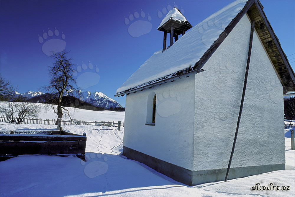 Paesaggio invernale suggestivo con una cappella innevata in Baviera