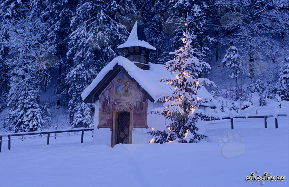 Weihnachten im Gebirge mit traditioneller Kapelle und verschneiten Gipfeln